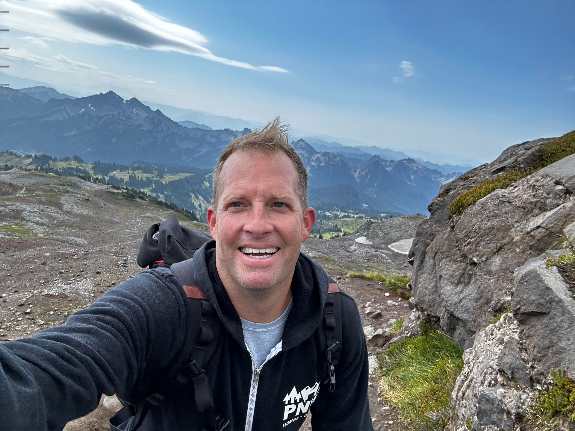 Ron Rougeaux on a Mount Rainier ridge in a PNW Homes Group hoodie